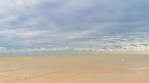 Dramatic clouds float on the coast of the blue sea Stock Photos
