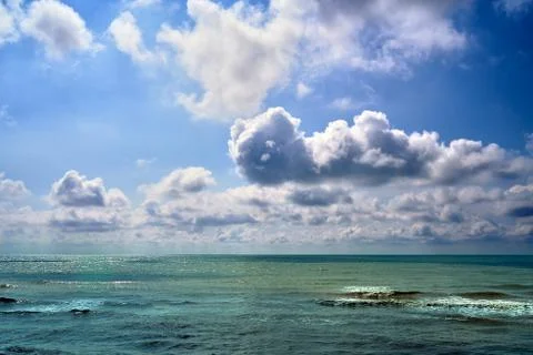 Dramatic clouds float on the coast of the blue sea Stock Photos