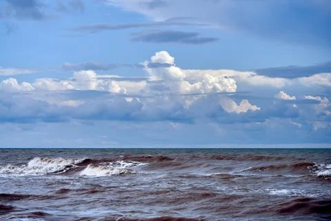 Dramatic clouds float on the coast of the blue sea Stock Photos