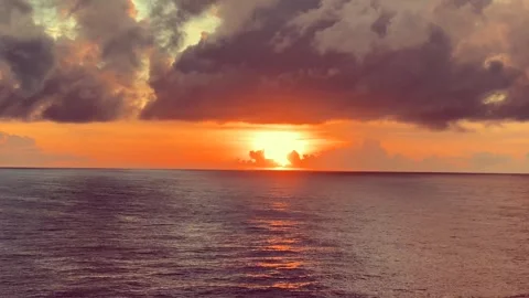 Dramatic clouds gather over the ocean as the sun sets, casting an orange gl.. Stock Footage 338282594
