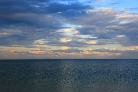 Dramatic clouds gather over the vast ocean horizon at dusk Stock-Fotos
