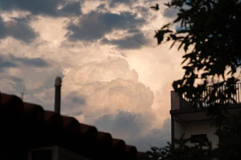 Dramatic clouds glow softly above rooftops Stock Photos