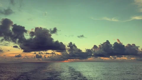 Dramatic clouds hover over a serene ocean at sunset creating a peaceful sce.. Stock Footage 338280507