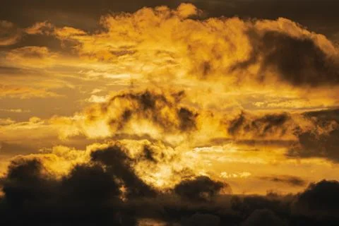 Dramatic clouds illuminated rising of sun in sky to change weather. Natural Stock Photos