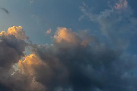 Dramatic clouds illuminated by sunset over a serene landscape at twilight Stock Photos