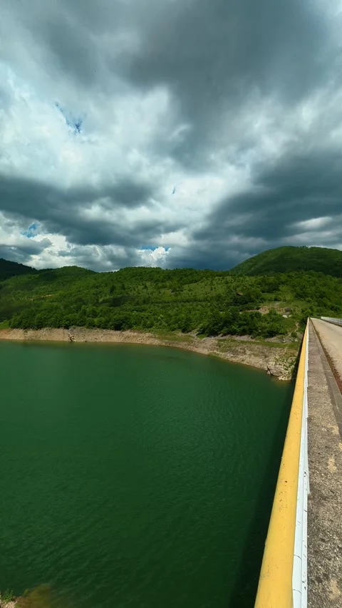 Dramatic clouds loom above a calm green lake. Zavoj Lake, Serbia. Vertical Stock-Footage 337495887