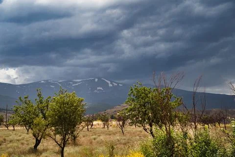 Dramatic clouds loom over distant snow-capped mountains Foto stock