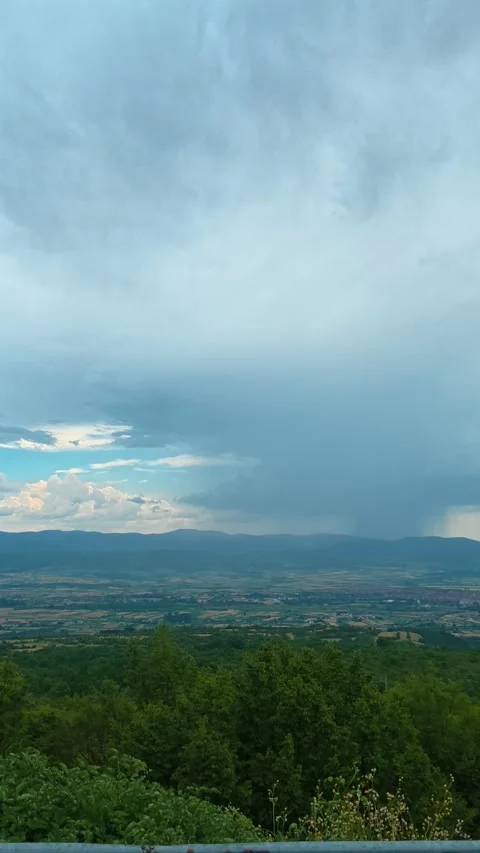 Dramatic clouds loom over a vast green valley. Pirot City, Vertical 스톡 동영상 341882282