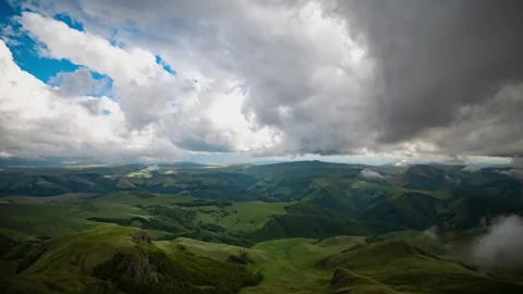 Dramatic clouds moving over green rolling hills and valleys in slow motion. Stock Footage 337358663