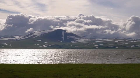 Dramatic clouds moving over a snow-capped mountain and lake Stock Footage 340260013