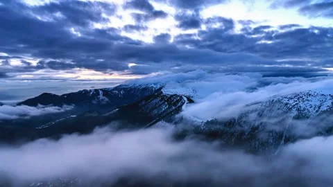 Dramatic clouds moving over snow-capped mountains at dawn. Stock Footage 341131419