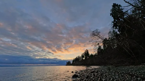 Dramatic clouds over deserted rocky shoreline with waves slowly hitting the Stock Footage 129657049