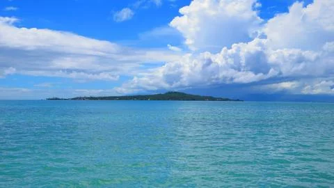Dramatic Clouds Over Distant Tropical Island Seen From Ocean Foto stock