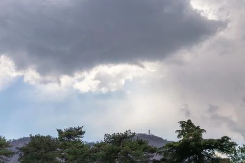 Dramatic Clouds Over Forested Landscape With Sunbeams Streaming Through Gaps Stock Photos
