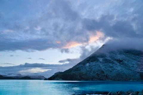 Dramatic clouds over mountains and fjord at twilight Stock Photos