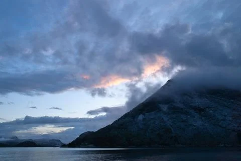 Dramatic clouds over mountains and fjord at twilight Stock Photos