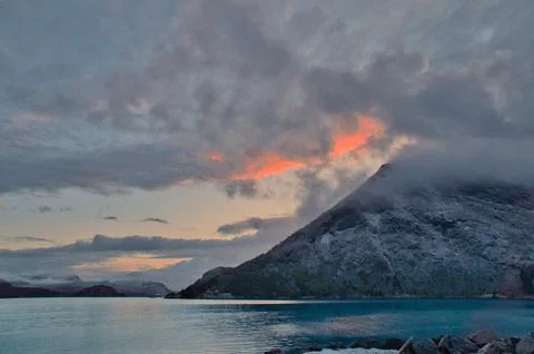 Dramatic clouds over mountains and fjord at twilight Stock Photos