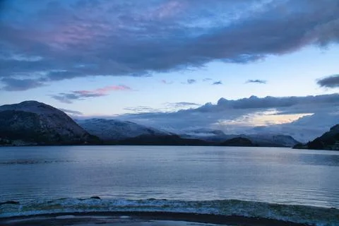 Dramatic clouds over mountains and fjord at twilight Stock Photos