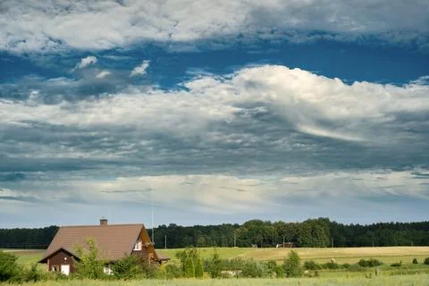 Dramatic clouds over rural countryside with farmhouse and summer fields 库存照片