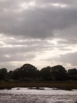 Dramatic clouds over silhouette treeline above coast Foto stock