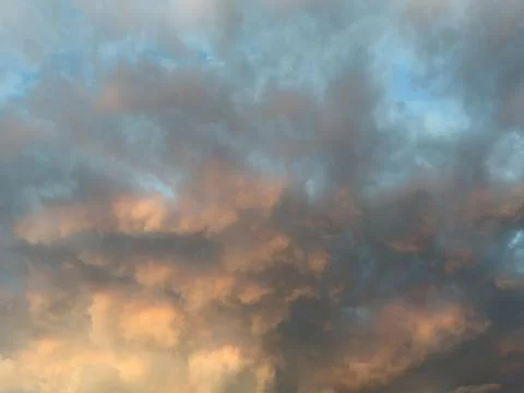 Dramatic clouds paint the sky in orange and gray Stock Photos