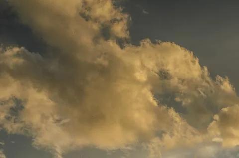 Dramatic clouds painted in warm hues fill the evening sky above a tranquil .. Stock Photos