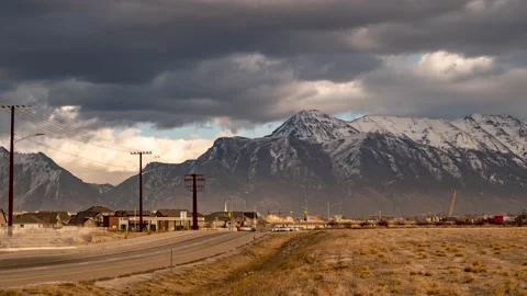 Dramatic clouds roll by the rugged snow capped mountains as rush hour 스톡 동영상 146618713