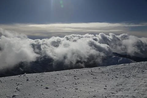 Dramatic clouds rolling below a snowy mountain summit Foto stock
