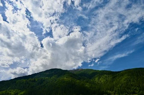 Dramatic Clouds Rolling Over Lush Green Mountain Slopes Фото