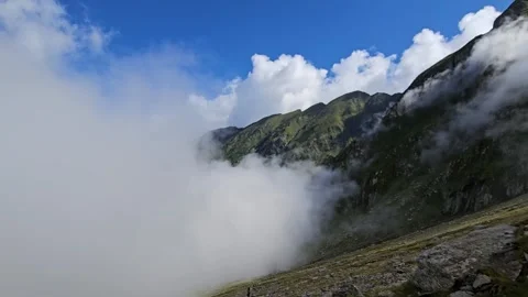 Dramatic clouds rolling over a steep mountain slope with a tiny hiker. Stock Footage 344041750