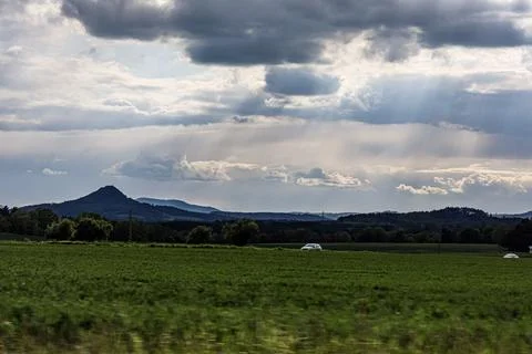 Dramatic clouds with sunbeams over rolling hills and a green meadow Foto stock