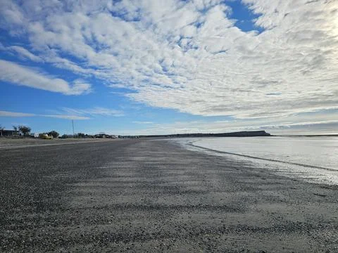 Dramatic Cloudscape Above Remote Playa Larralde Shore Stockfoto's