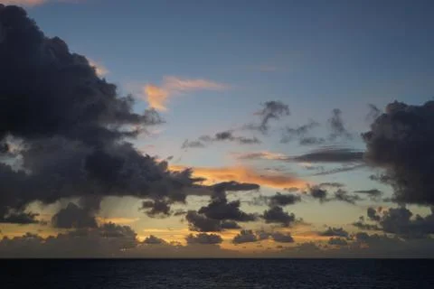 Dramatic cloudscape during sunrise over sea water Stock Photos