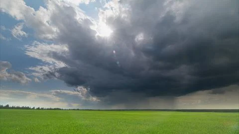 A Dramatic Cloudscape Enveloping a Vast Green Field Beneath an Expansive Evening Stock Photos