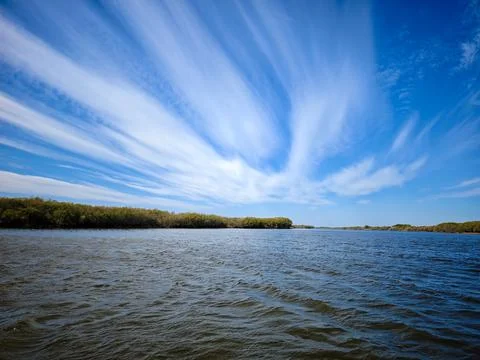 Dramatic cloudscape over calm lake with expansive forest horizon Stock Photos