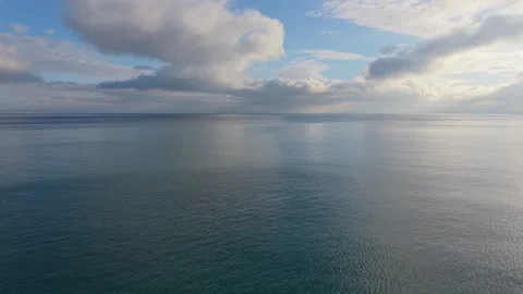Dramatic cloudscape over calm sea with mirror reflections and horizon Stock Footage 327840308