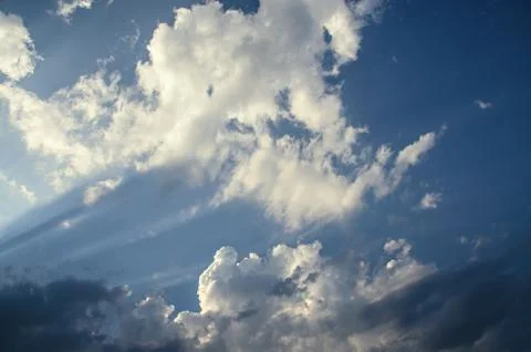 Dramatic cloudscape scene, colored sun lights on the blue sky, fluffy clouds Stock Photos