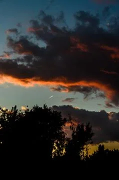 Dramatic cloudscape scene at orange sunset, colored sun lights on the blue sk Stock Photos