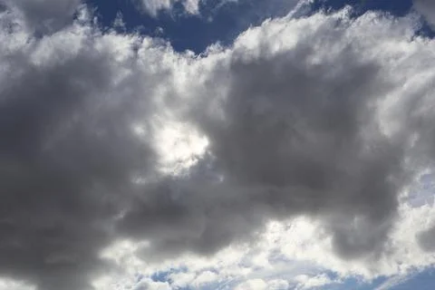 Dramatic cloudscape with sun peeking through dark, ominous storm clouds Stock Photos