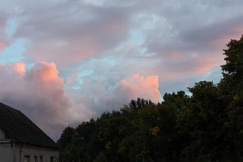 Dramatic cloudscape. Sunset sky, glowing pink and blue grey clouds after the  Stockfoto's
