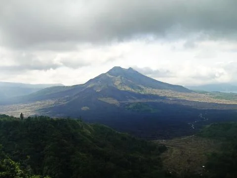 Dramatic, cloudy skies frame Mount Bromo's imposing silhouette over a vast Stock Photos