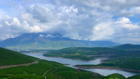 Dramatic cloudy sky above green valley and winding river landscape Stock Footage 310246547