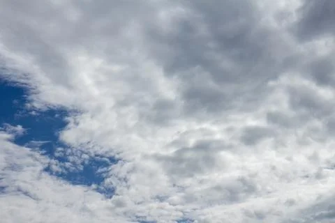 Dramatic cloudy sky with bright blue patches and white cumulus clouds 库存照片