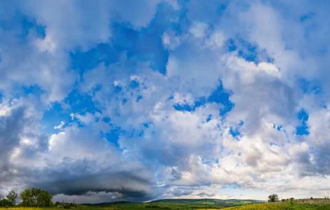 Dramatic cloudy sky with circular thunderstorm cloud over countryside hills Stock Photos