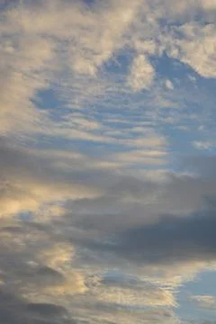 Dramatic cloudy sky closeup with warm sunset light and blue opening Stock Photos
