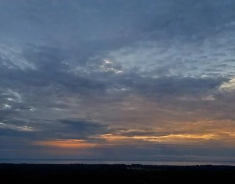 Dramatic Cloudy Sky at Dawn with Golden Light Over Ocean Horizon Stock Photos