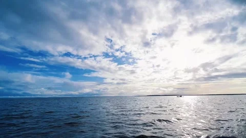 Dramatic cloudy sky over calm ocean with small boat on horizon Stock Footage 333309251