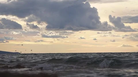 Dramatic cloudy sky over calm ocean waves during warm sunset Stock Footage 337410449