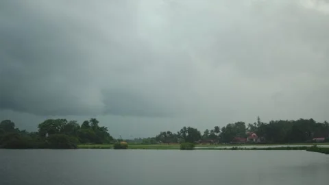 Dramatic cloudy sky over a calm river landscape with lush tropical shoreline Stock Footage 340841388
