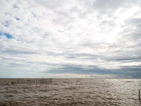 Dramatic Cloudy Sky Over Calm Ocean Sea with Traditional Bamboo Fish Trap S.. 写真素材